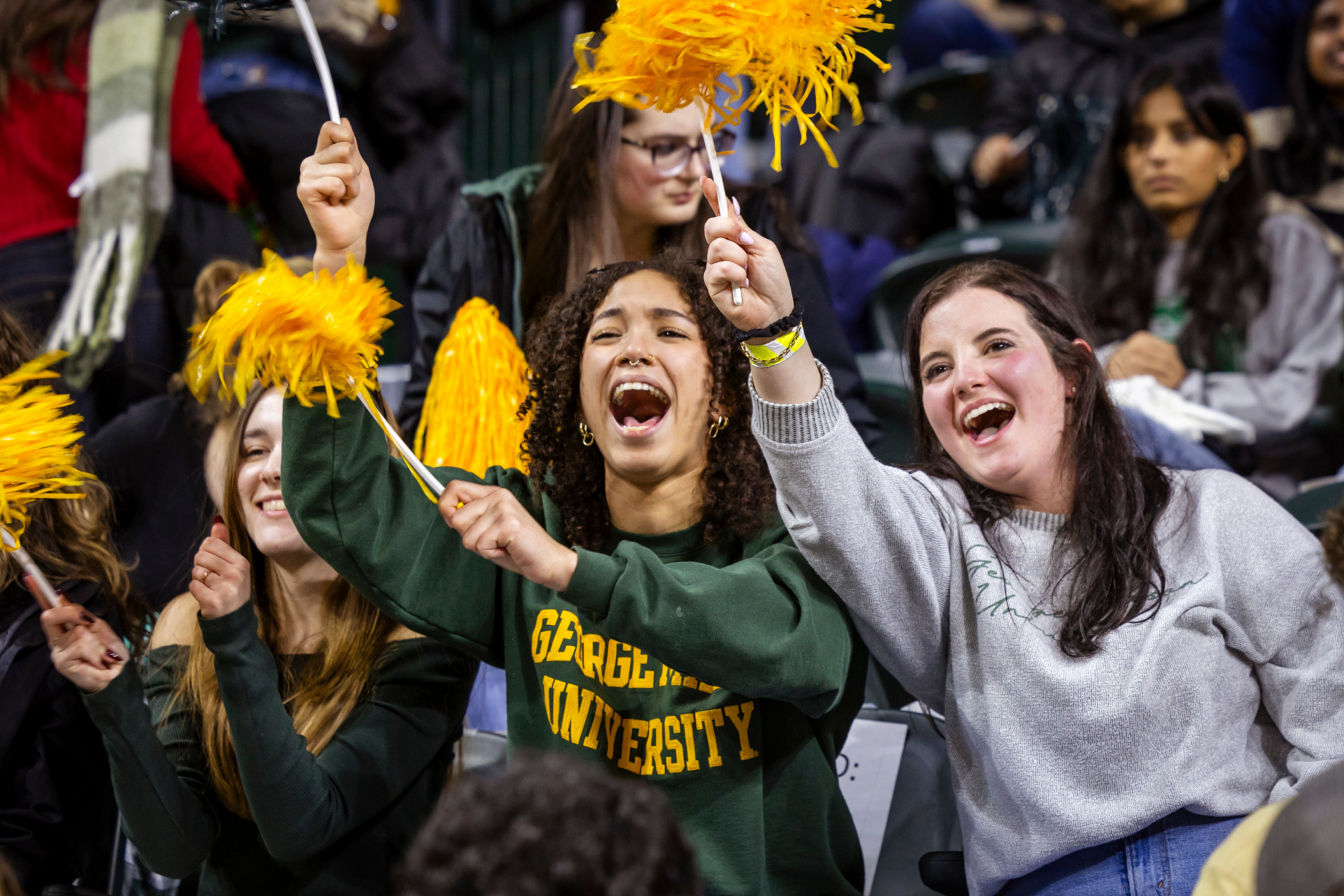 Several Mason fans in the stands at the EagleBank Arena, cheering on the Patriots